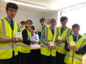 group of students in hi vis jackets holding fabricated metal signs